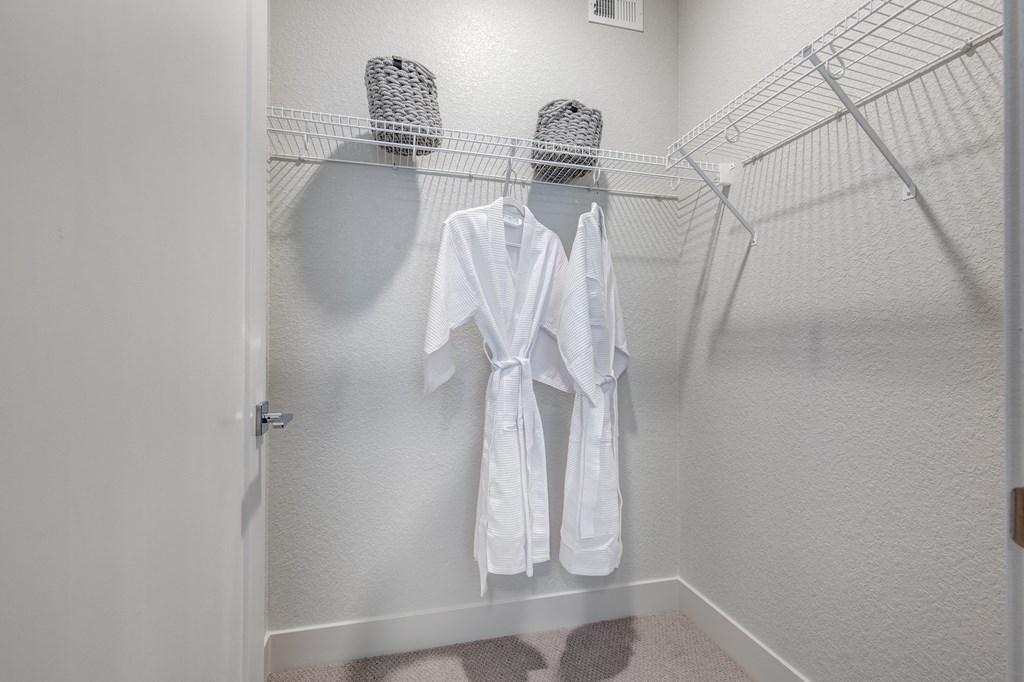 a walk in closet with two white robes hanging on a rack
