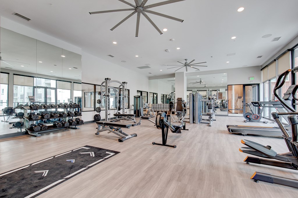a spacious fitness center with weights and cardio equipment and large windows