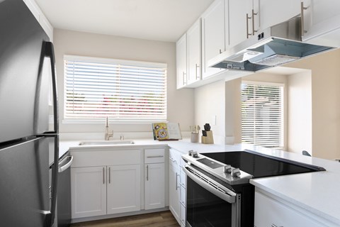 a kitchen with white cabinets and a black counter top