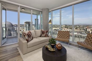 A living room with a view of the cityscape outside the large windows.