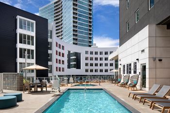 A pool area with chairs and a building in the background.