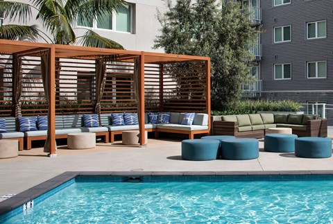 A pool area with a wooden structure and cushions.