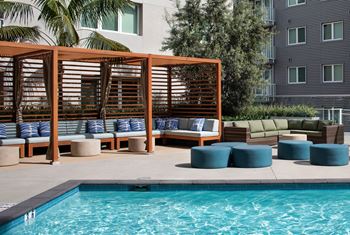 A pool area with a wooden structure and cushions.