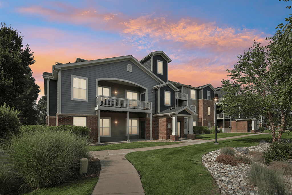 A modern two-story house with a balcony and a small garden in front.