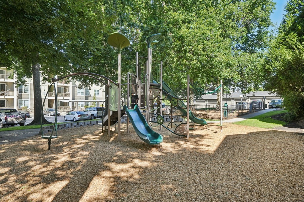 A playground with a green slide and a brown ground.