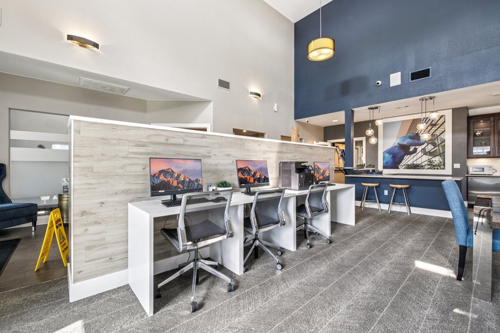 A modern office space with a white desk, blue chairs, and a yellow caution sign.