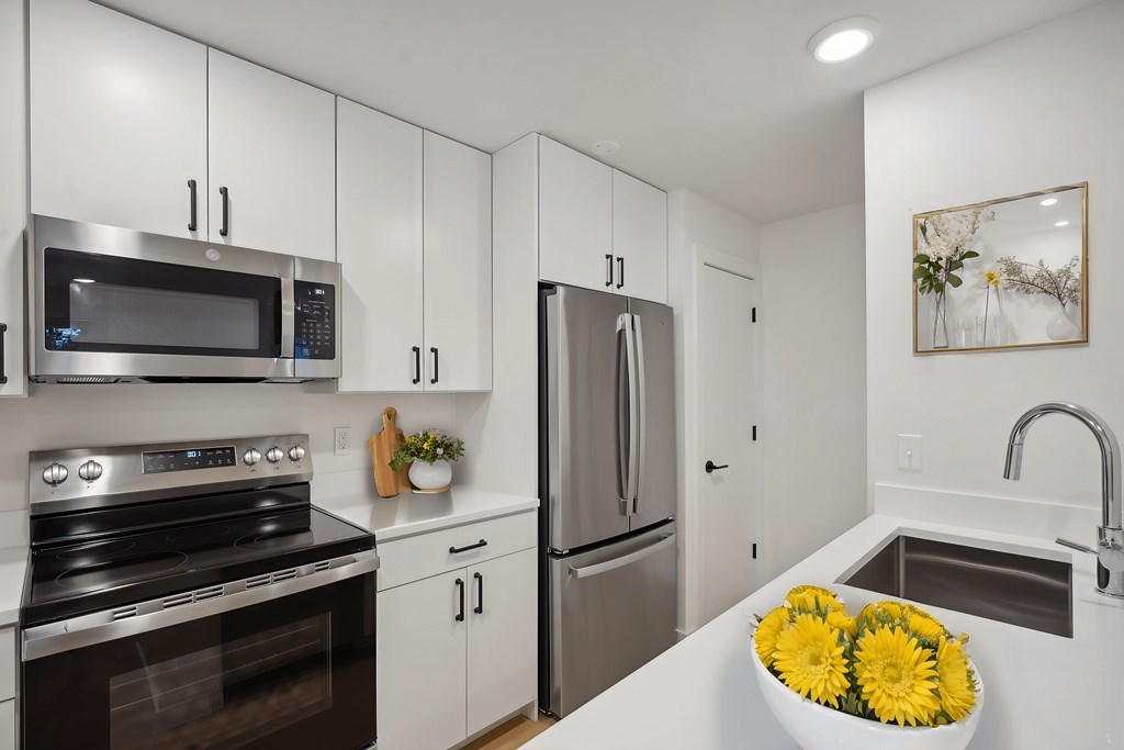 A modern kitchen with white cabinets and stainless steel appliances.