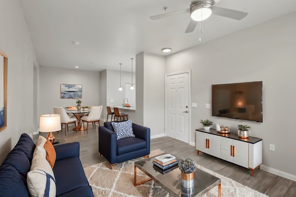 A living room with a blue couch and a television on a cabinet.