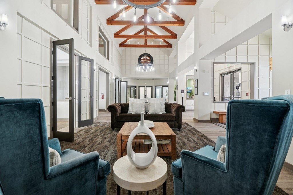 A large, modern room with a high ceiling and a mix of dark and light furnishings.