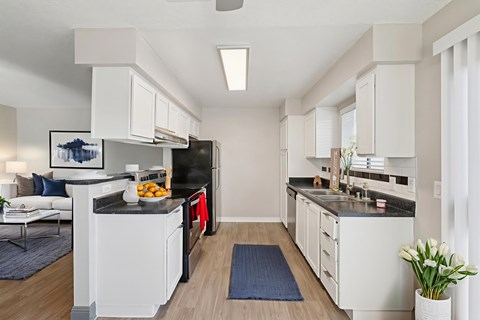 A modern kitchen with white cabinets and a black countertop.