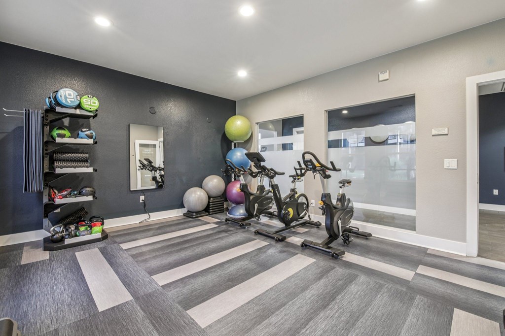 A room with a grey floor and a black wall with a white door and a white light switch.