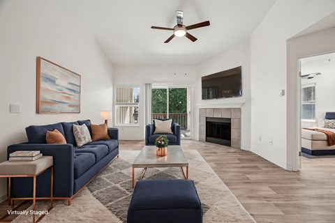 A living room with a blue couch and a painting on the wall.