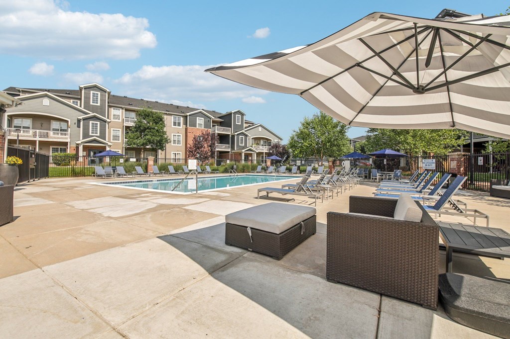 A sunny day at the poolside with a large umbrella providing shade.