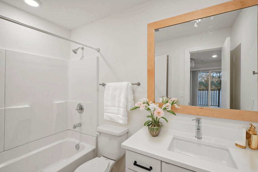 A white bathroom with a large mirror and a white toilet.