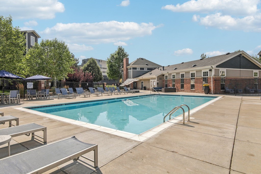 A swimming pool surrounded by lounge chairs and umbrellas.