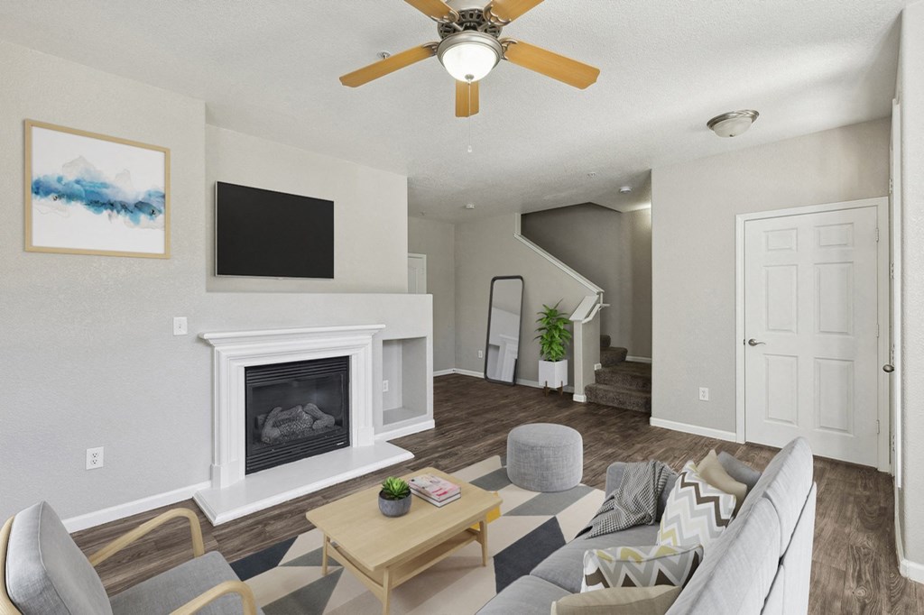 an open living room with a fireplace and a ceiling fan