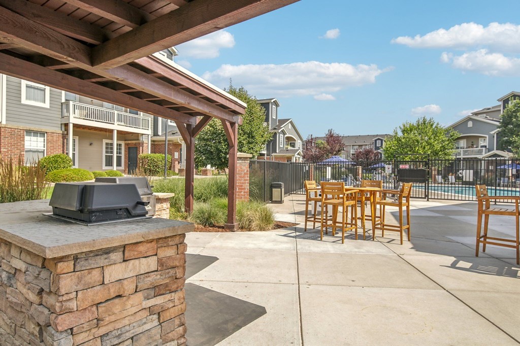 A patio with a stone pillar and wooden chairs.