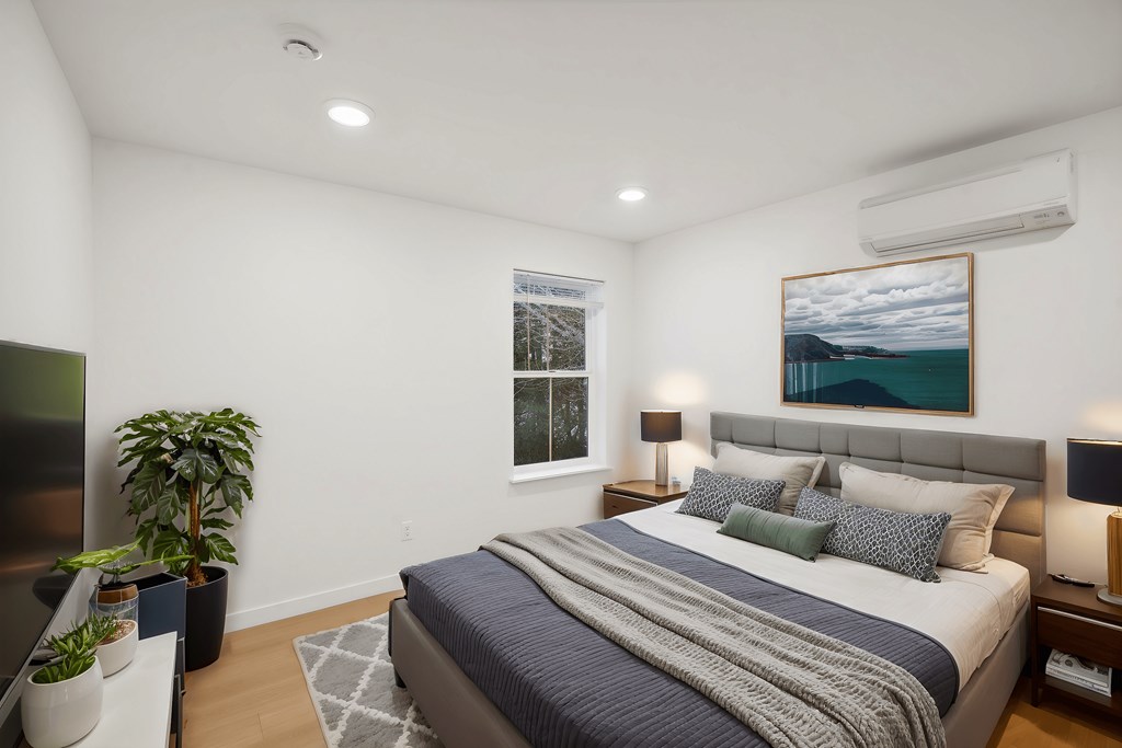 A bedroom with a large bed and a painting on the wall.