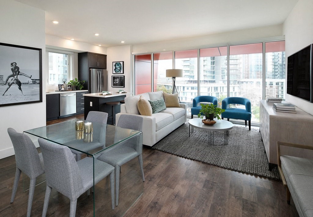 A modern living room with a glass table and grey chairs.