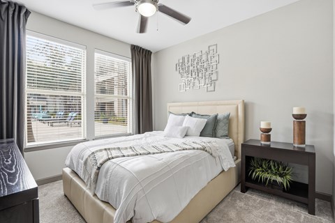 A bedroom with a large bed and a ceiling fan.
