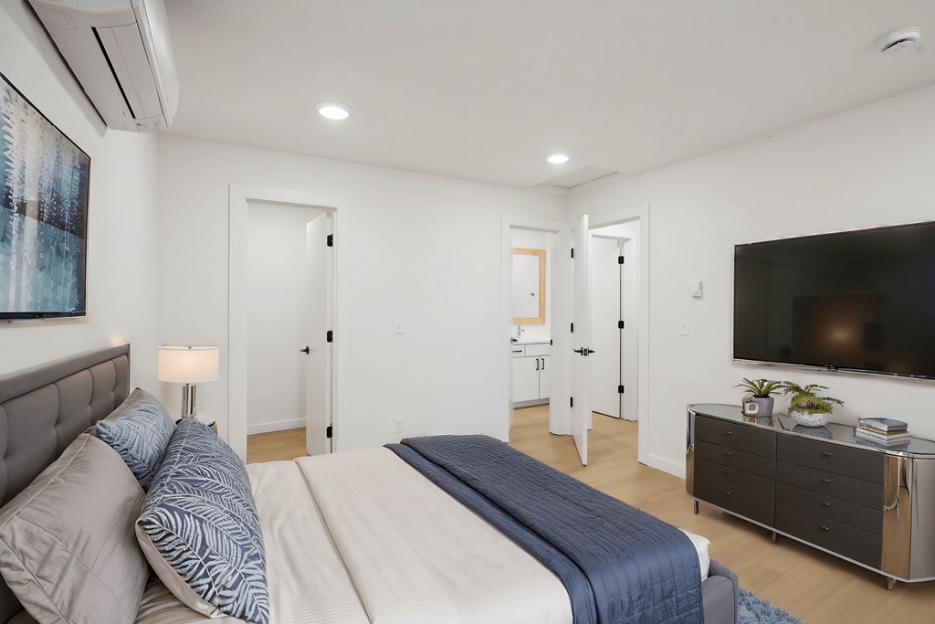 A bedroom with a large bed and a flat screen TV mounted on the wall.