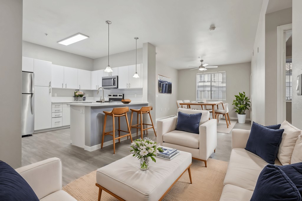 A modern living room with a kitchen in the background.