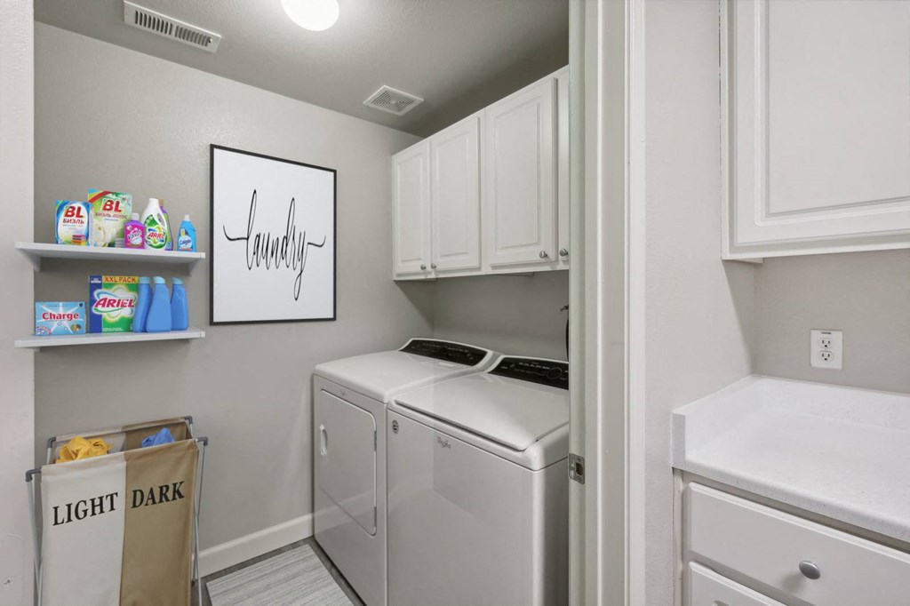 a laundry room with a washer and dryer and white cabinets