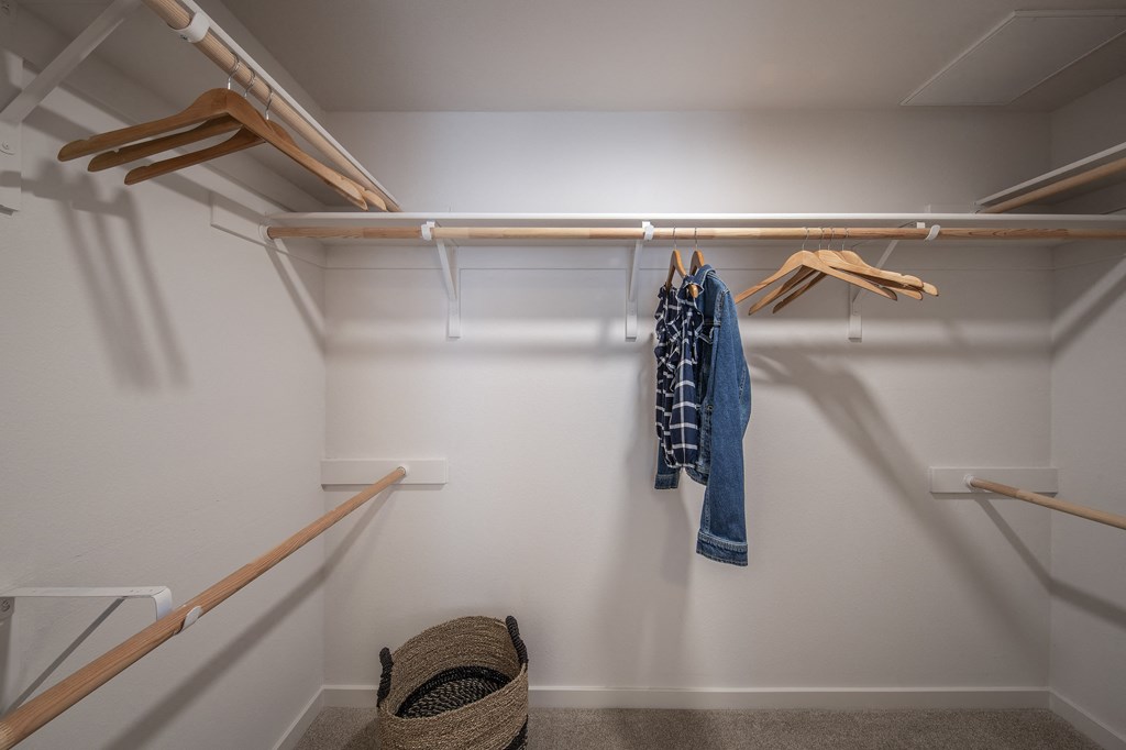 a walk in closet with a rack of clothes and a basket on the floor