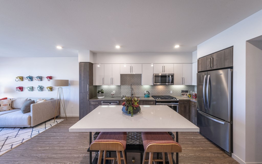 a kitchen with stainless steel appliances and a white island with four chairs