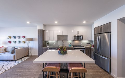 a kitchen with stainless steel appliances and a white island with four chairs