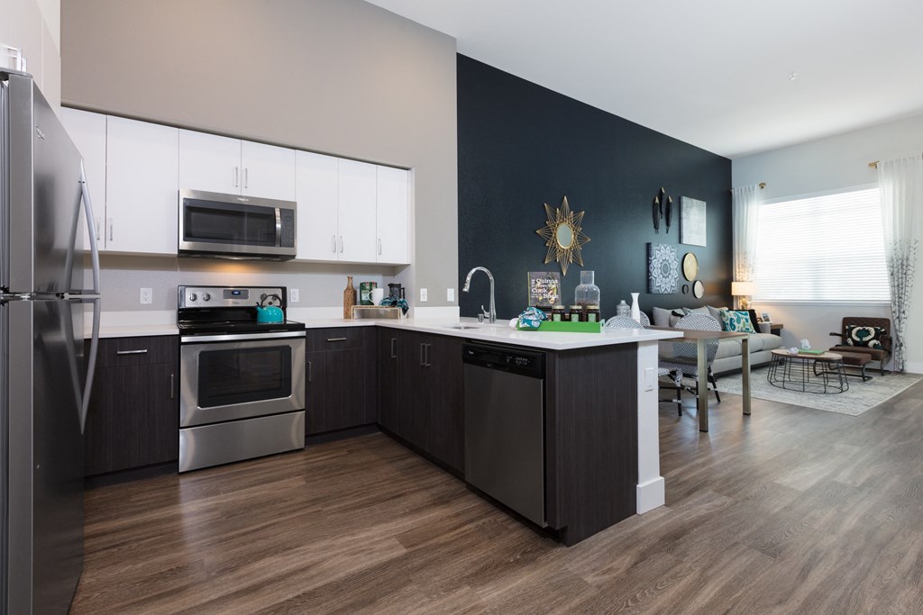 a kitchen with white cabinets and stainless steel appliances and a table with a chair in the background