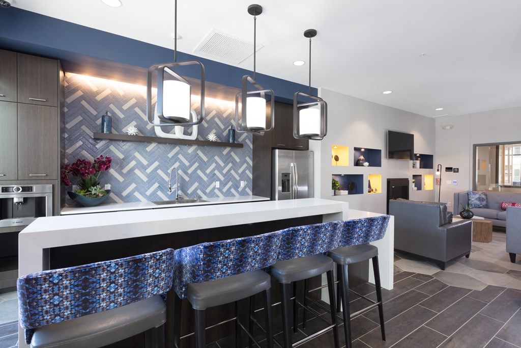 a kitchen with a bar and a living room in the background