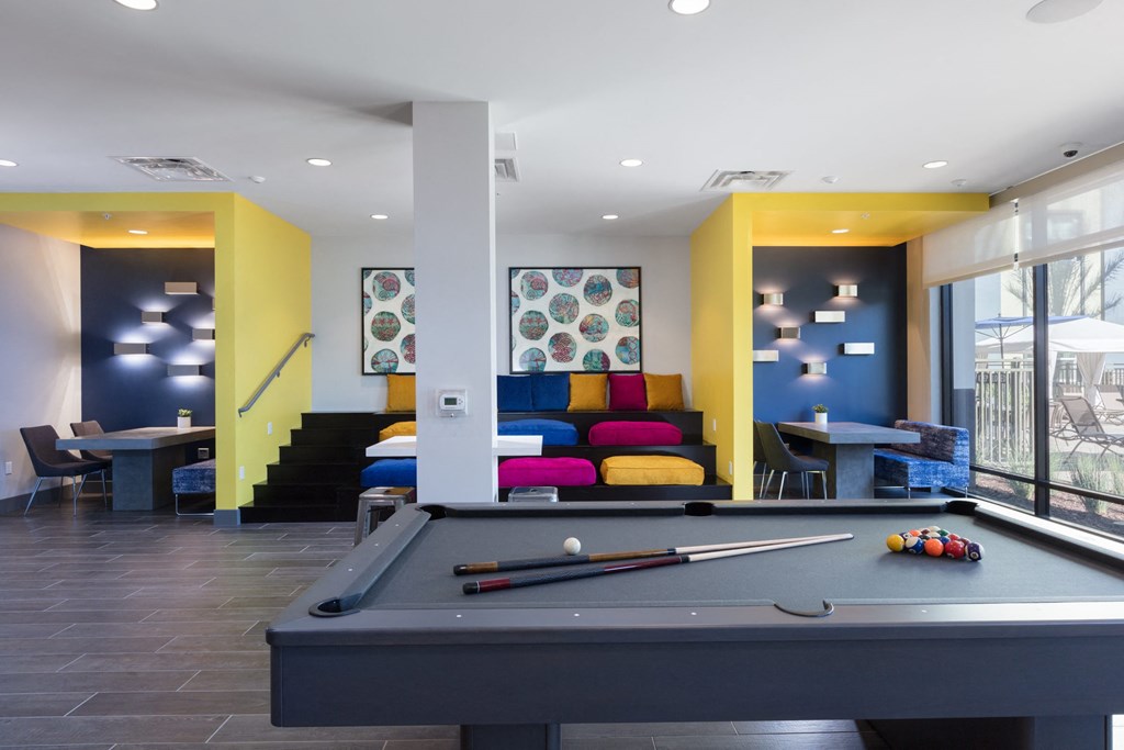 a pool table with a colorful couch in the background