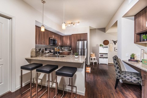 a kitchen with a bar and stools in front of a counter top