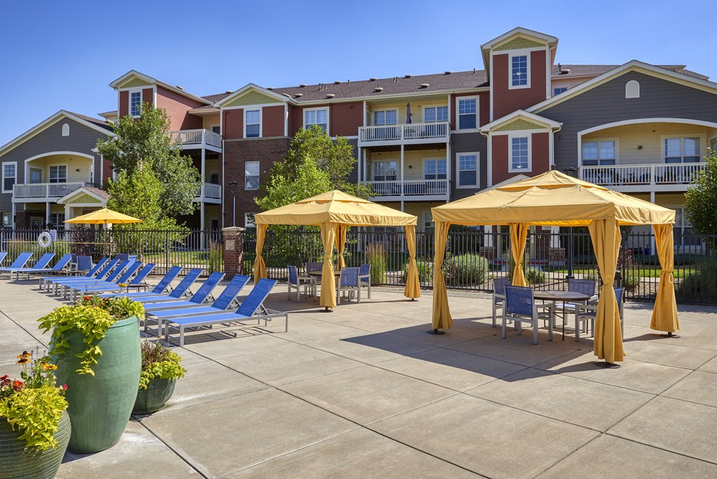an outdoor patio with yellow umbrellas and chairs at an apartment complex