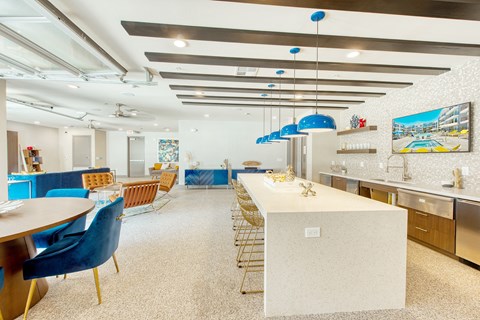 A kitchen with a long table and blue chairs.