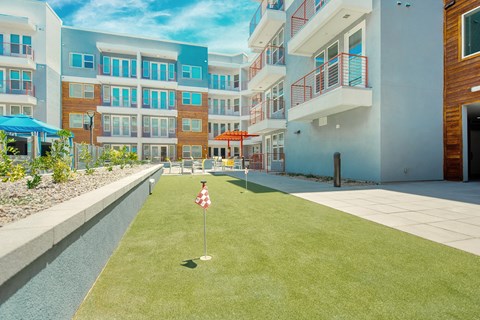A grassy area with a red and white flag in front of apartment buildings.