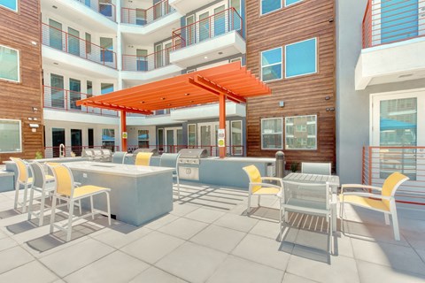 A patio with a table and chairs and a red umbrella.