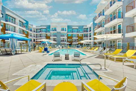 A large pool surrounded by yellow chairs and umbrellas.