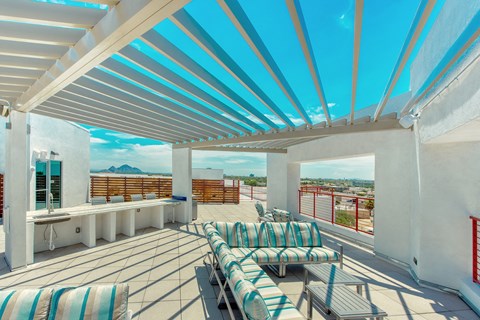 A patio with a white roof and striped cushions.