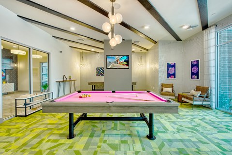 A pool table in a room with a TV on the wall.