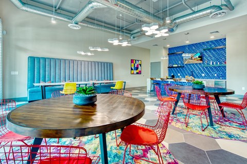 A room with a round wooden table surrounded by red chairs.