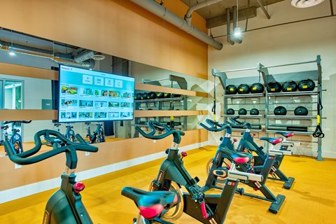 A gym with exercise bikes and a screen showing a workout routine.