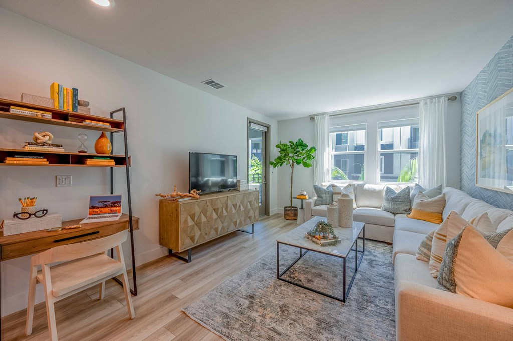 A living room with a white couch, a wooden chair, a coffee table, and a television.