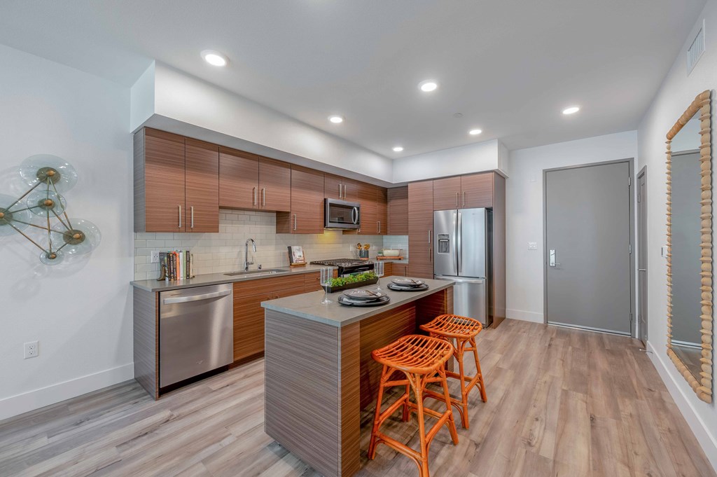 A modern kitchen with wooden cabinets and a stainless steel refrigerator.