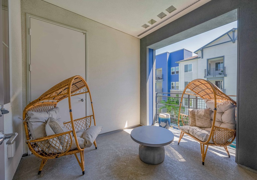 A room with two wicker chairs and a table.