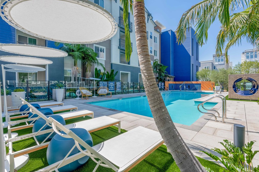 A pool area with lounge chairs and umbrellas.