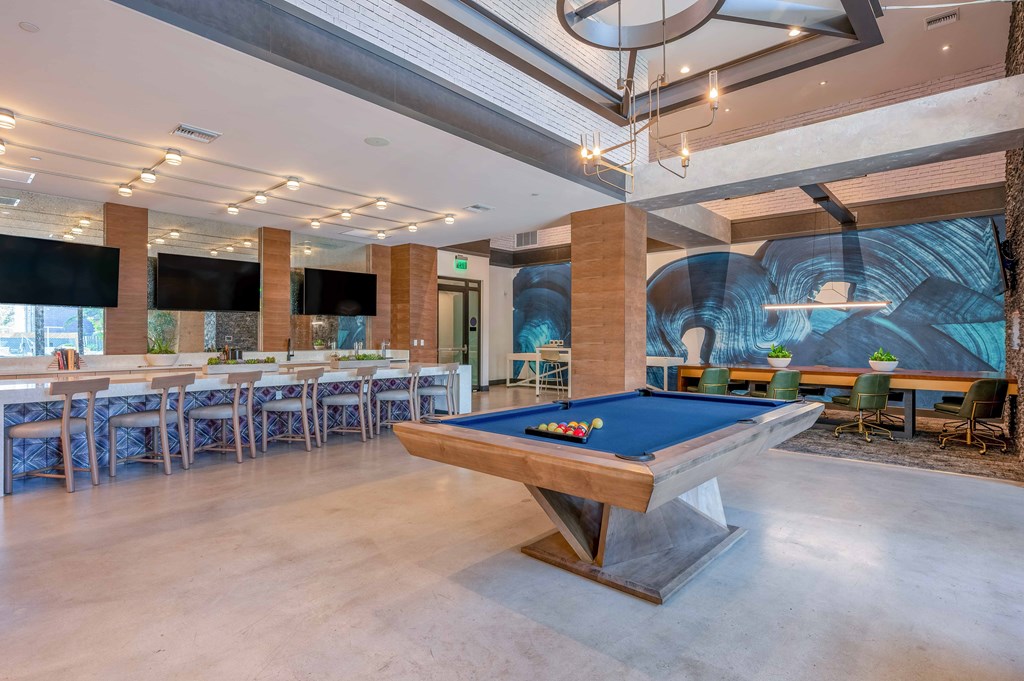 A pool table is in the middle of a room with a long table and chairs.