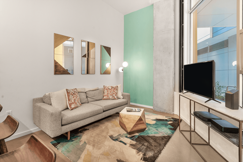 A living room with a grey couch and a rug.