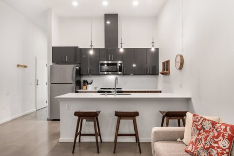 A modern kitchen with a bar stool and a couch.